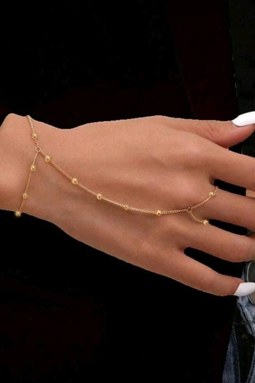 Gold beaded hand chain worn across the wrist